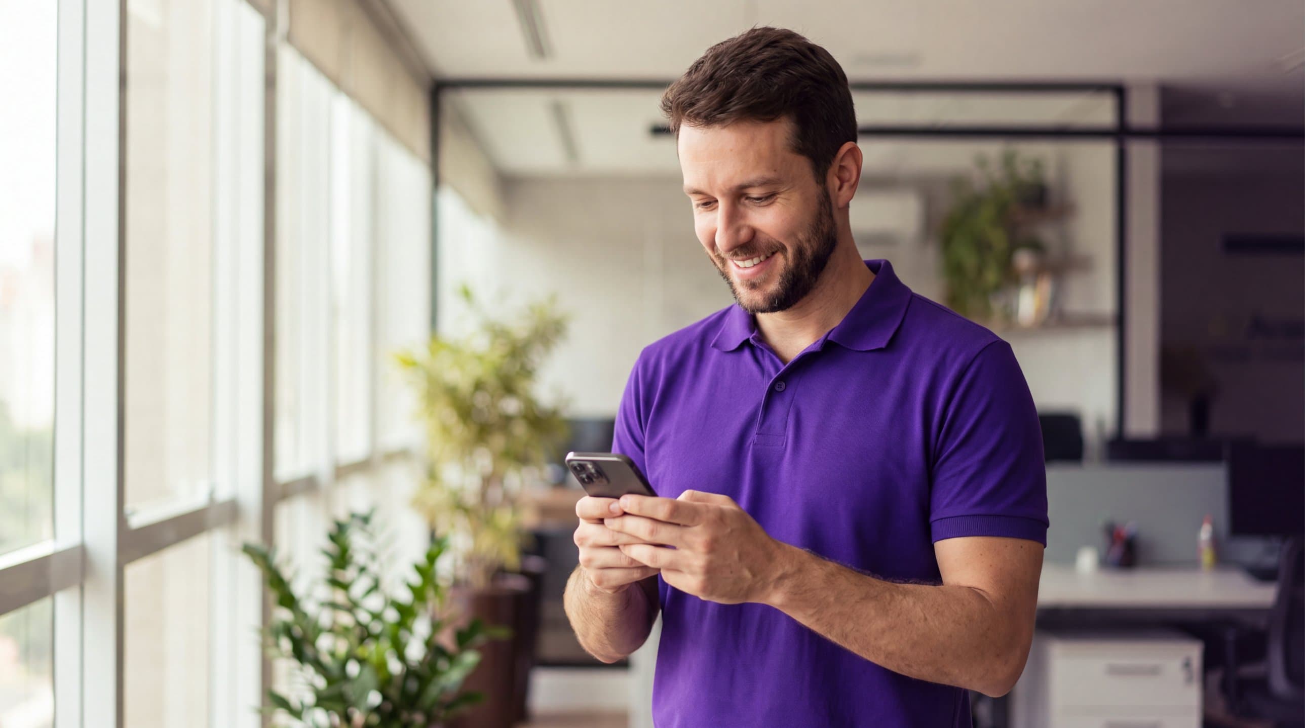 Especialista da Avantar sorrindo enquanto responde uma mensagem no celular