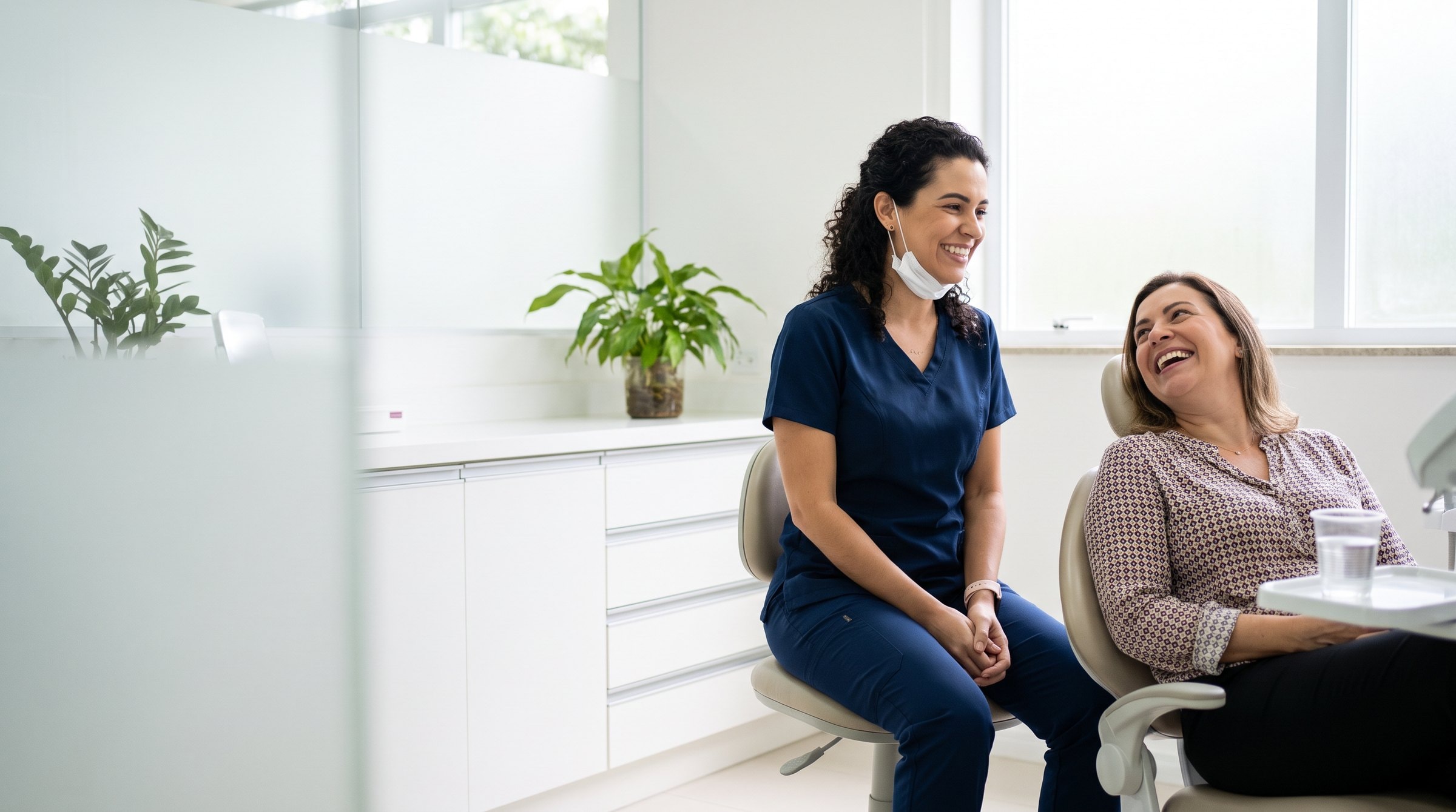 Dentista conversando com uma paciente tranquila no consultório.